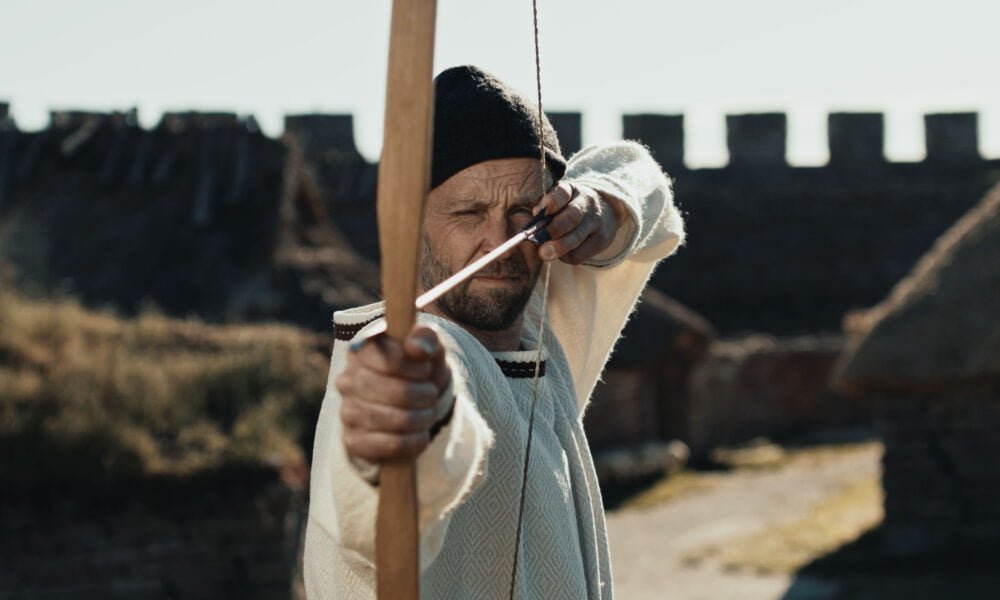 n man siktar med pil och pilbåge.