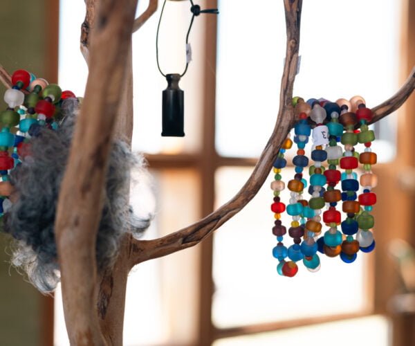 Halsband i glaspärlor hänger på en pinne.