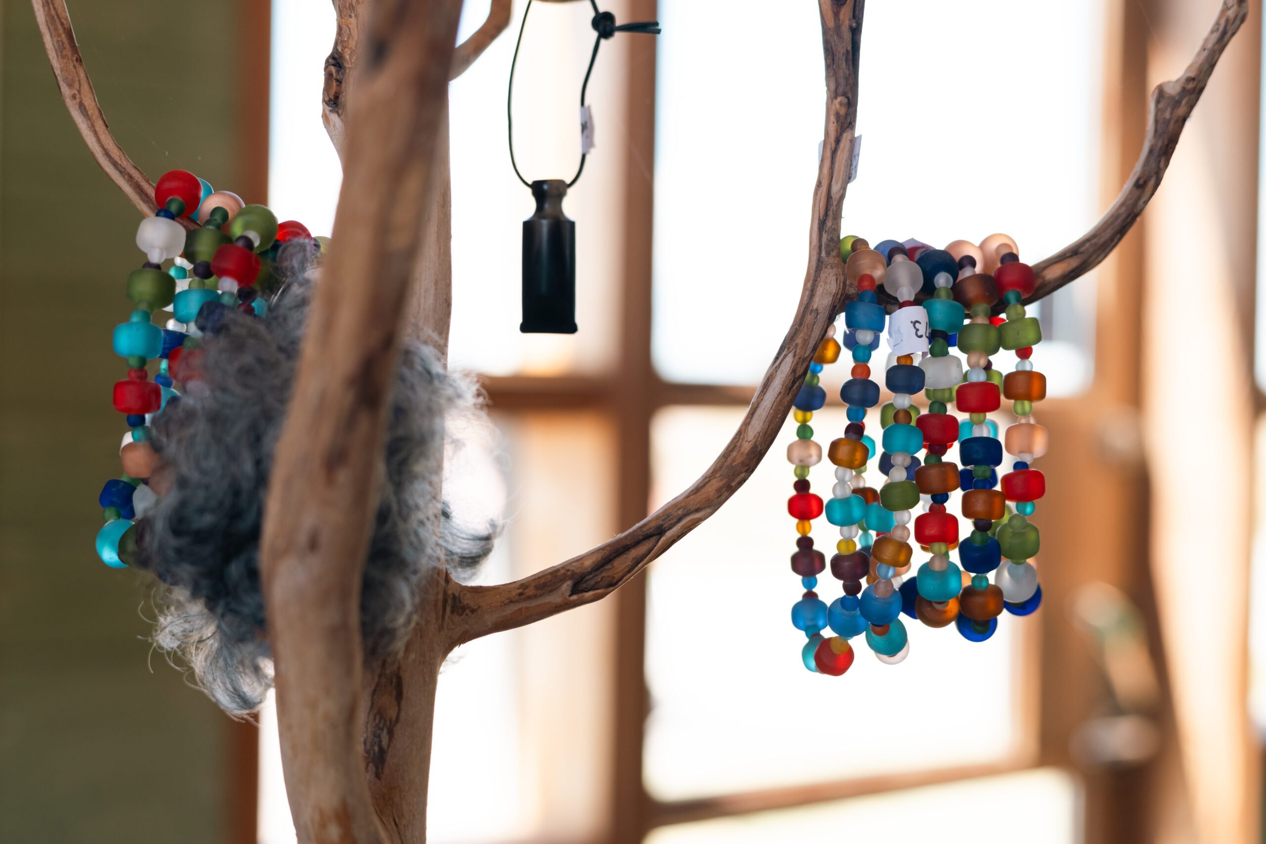 Halsband i glaspärlor hänger på en pinne.
