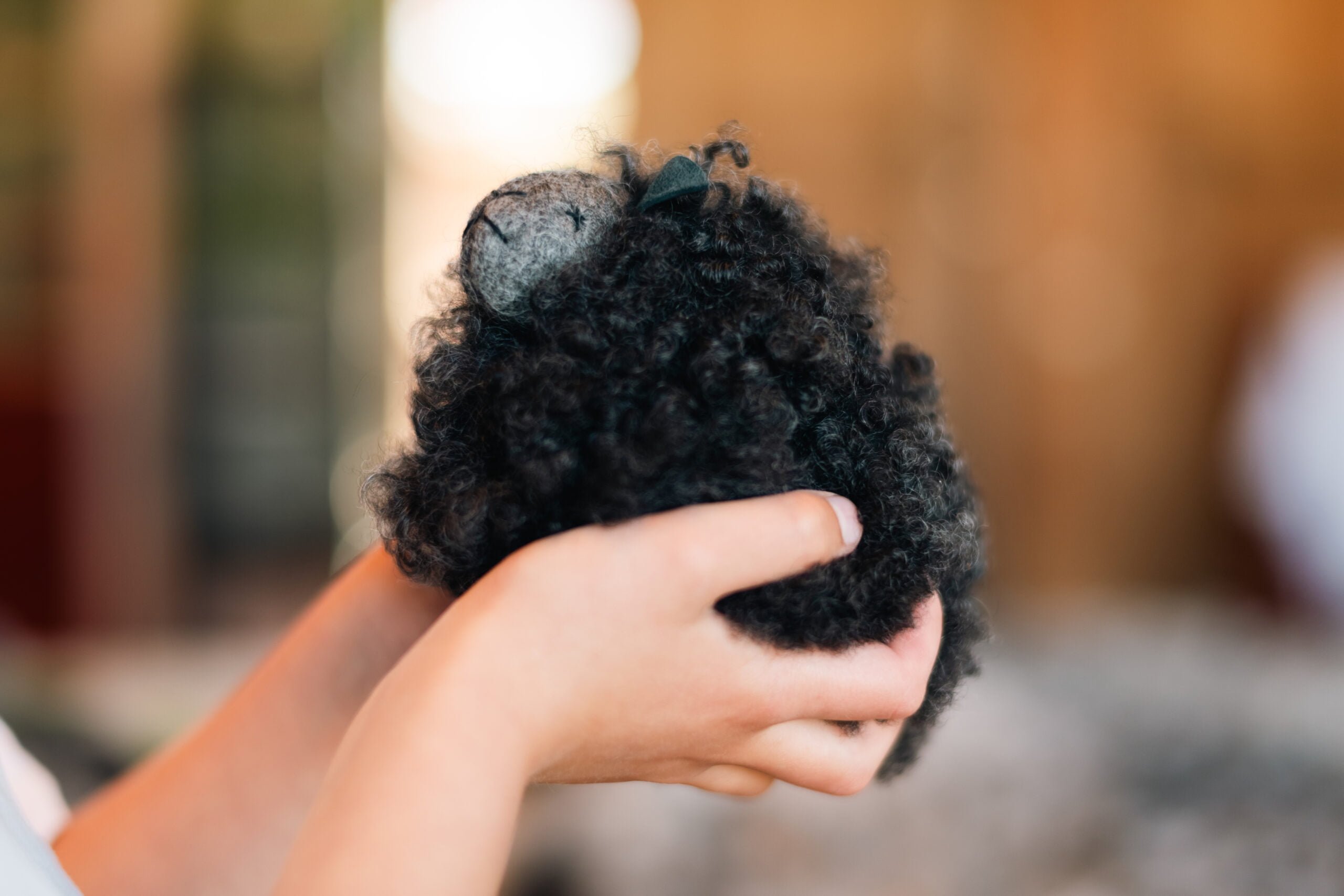 Två händer håller i ett gosedjursfår.