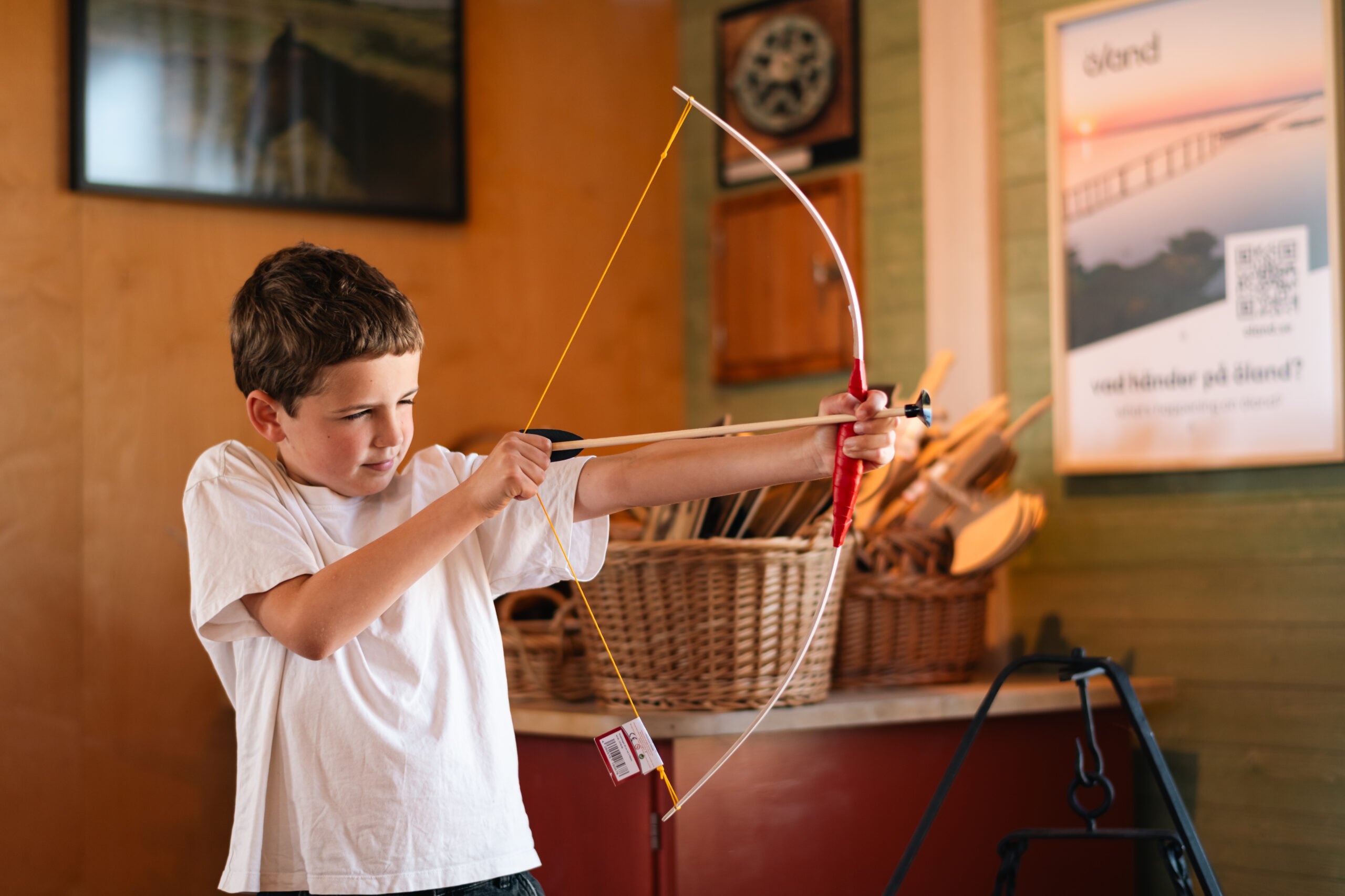 En pojke spänner en leksakspilbåge i en butik.