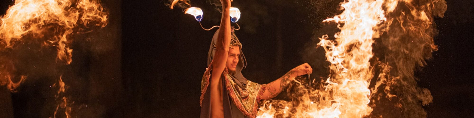 Man som jonglerar med eld i mörker