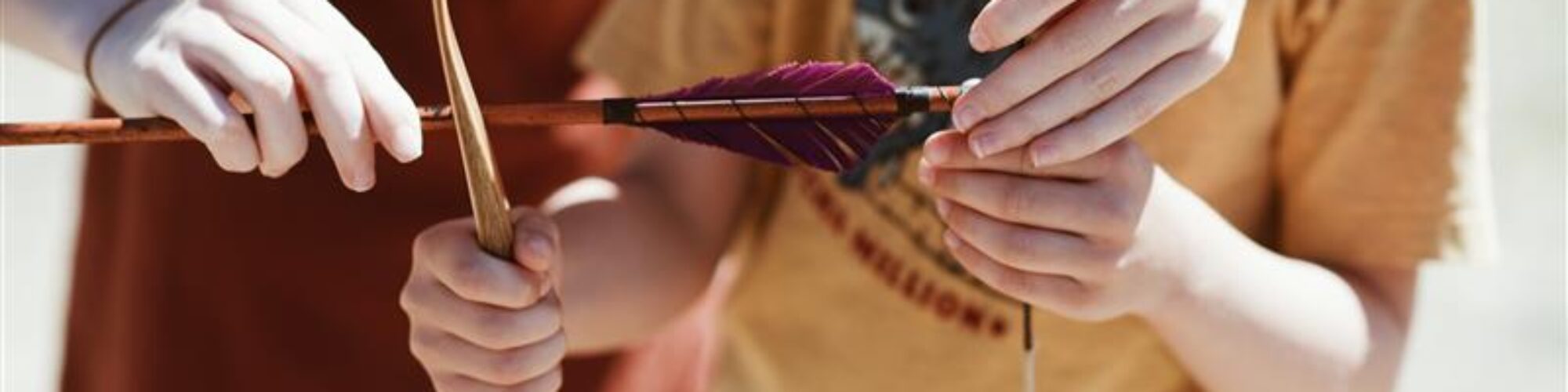 Barn få hjälp med att fästa pil på bågsträng.